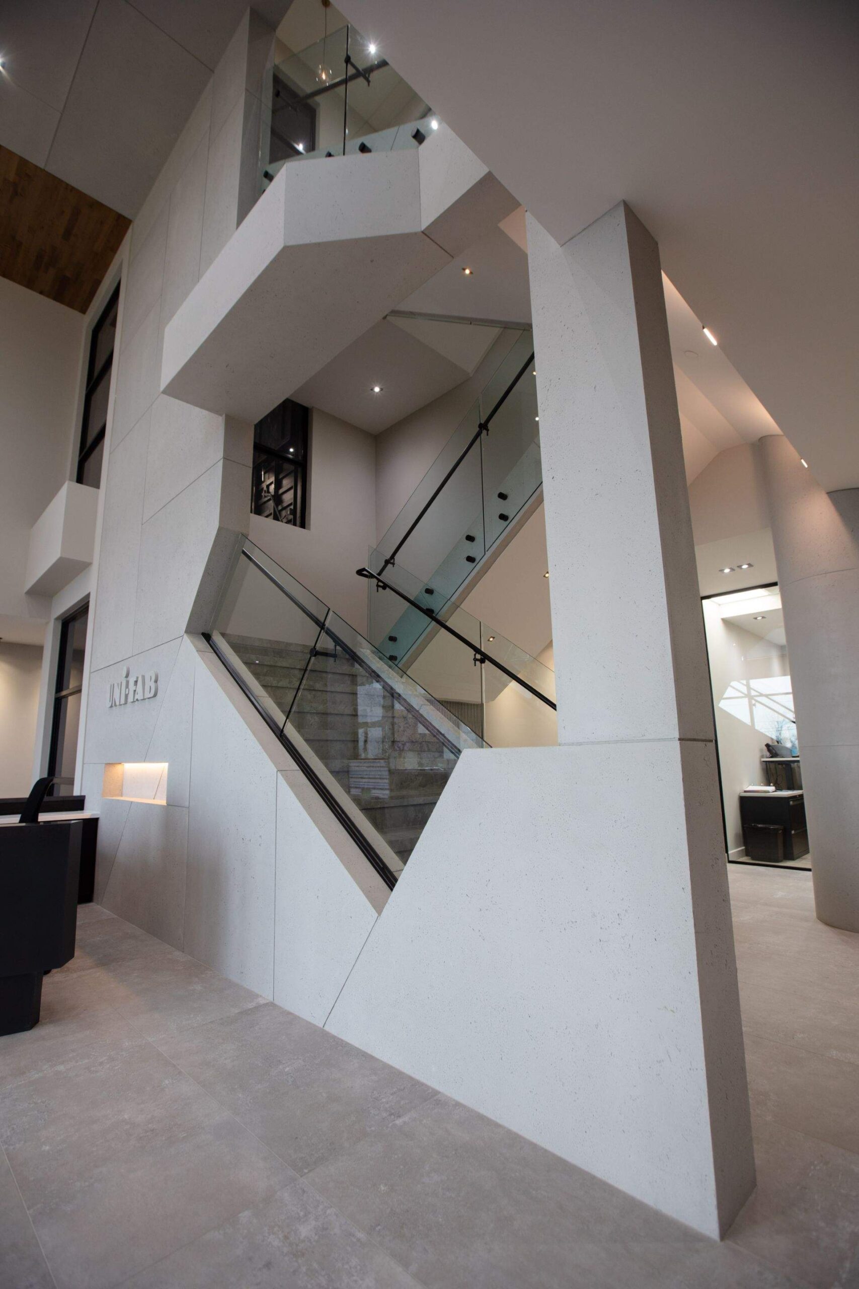 Modern office with glass railings and staircase, featuring lightweight concrete cladding and industrial design.