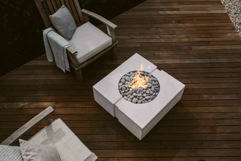 Wooden deck with two outdoor chairs and a concrete fire pit. 