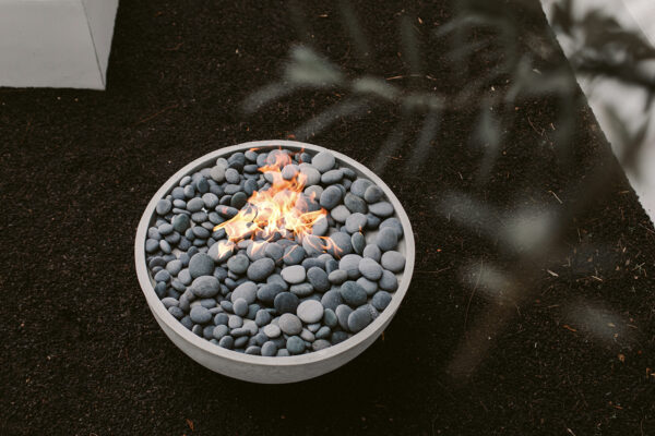 Circular lit concrete fire pit sitting in a garden.