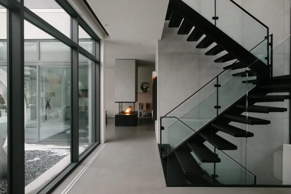 A modern staircase with black railing and glass walls, showcasing modern interior design and concrete cladding.