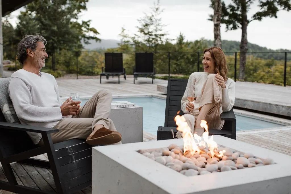 Man and woman sit next to a Dekko concrete fire pit on a hardwood deck.