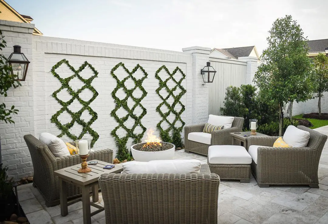 An outdoor living space on concrete tile with chairs, an ottoman and a round Dekko fire pit.