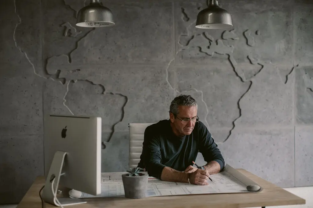 Male designer sitting at office desk reviewing design sketches. 