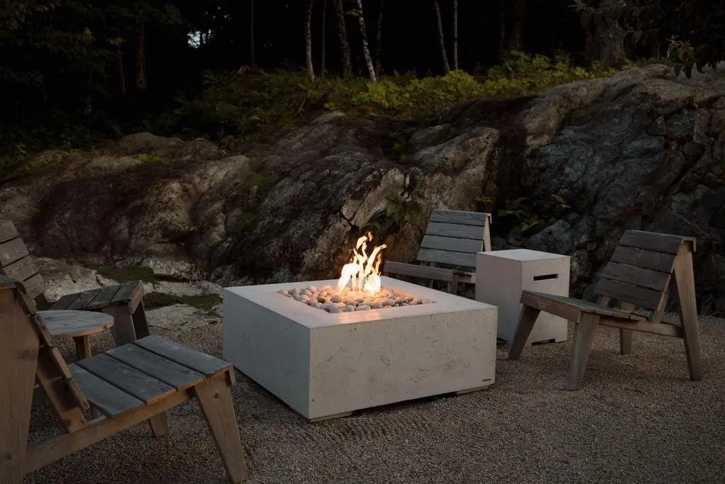 A Dekko concrete fire pit between four empty patio chairs.