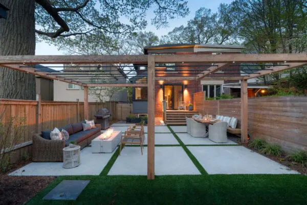 A large backyard with wooden fencing, a wooden covering, sofas and a Dekko fire pit from the Avera range.