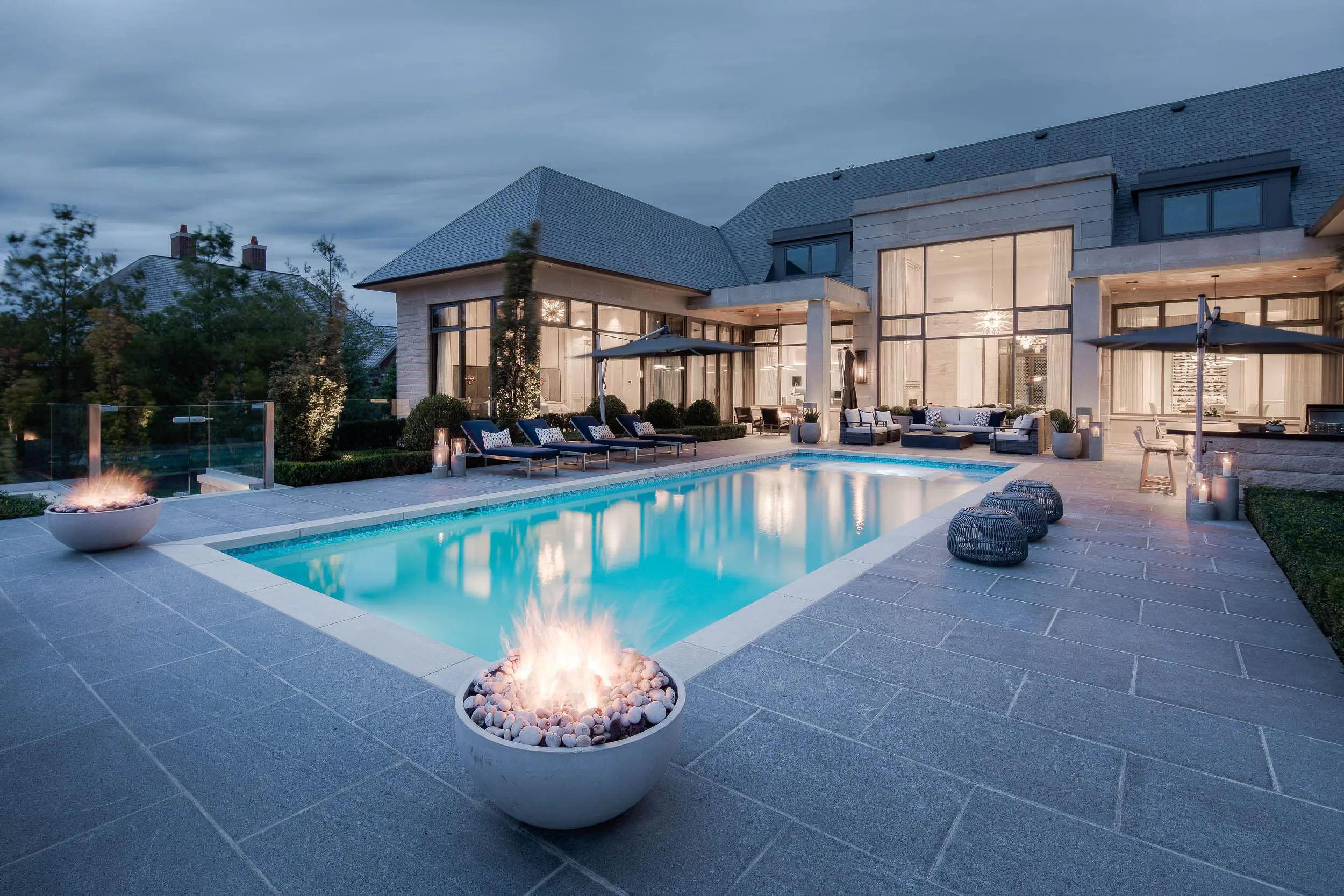 A Dekko lightweight concrete fire pit next to a pool in a backyard.