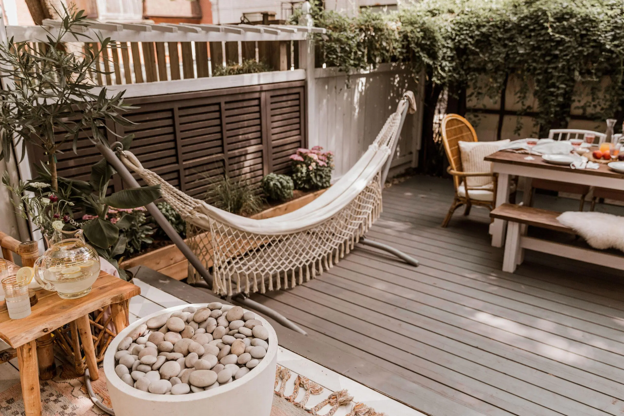 A Dekko lightweight concrete fire pit on a backyard patio with a hammock and dining furniture pieces.